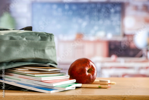 School backpack and school stuff with space for products on wooden desk in classroom  interior. Chalkboard wall background. Back to school. Copy space for school supplies and accessories. photo