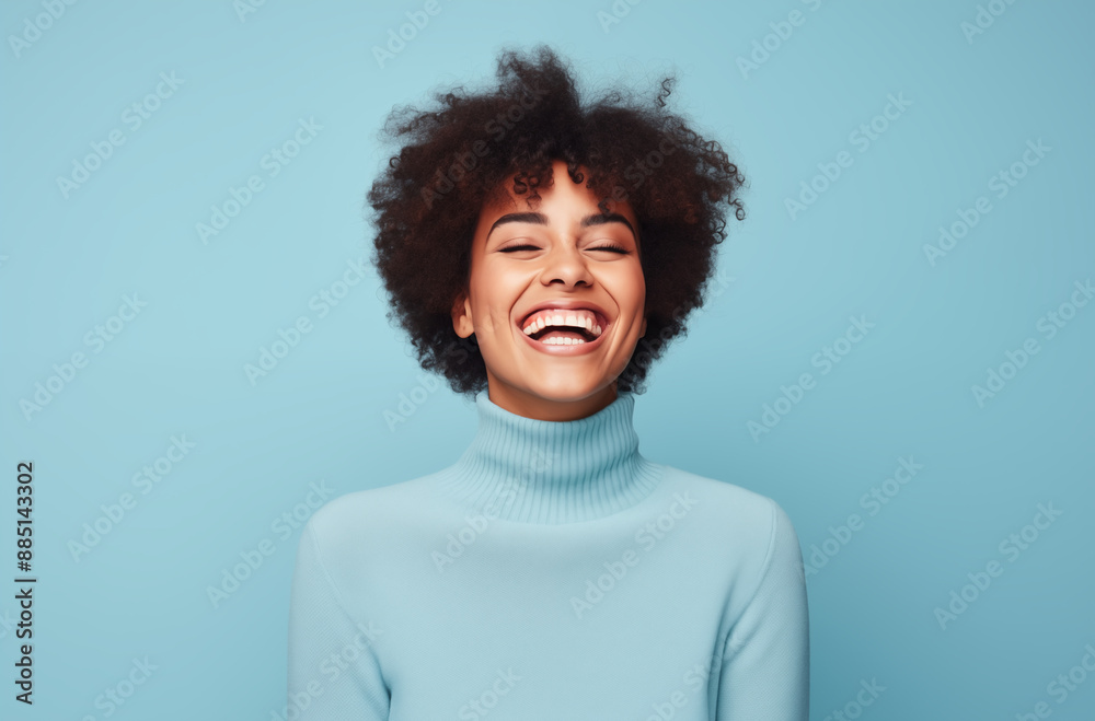 Obraz premium Happy woman in a light blue turtleneck sweater, laughing joyfully against a matching blue background, capturing a moment of pure happiness