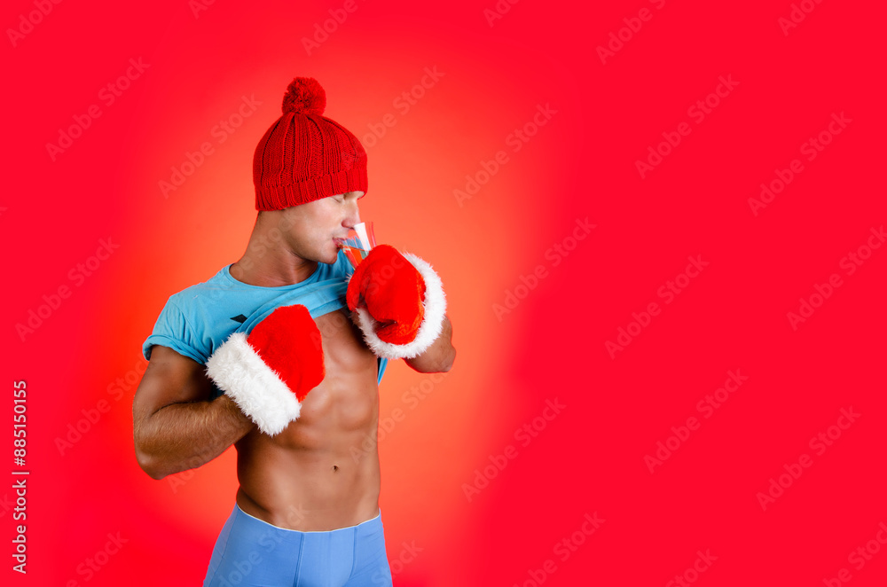 New Year's and Christmas. Handsome muscular man posing on a red background. New Year's and Christmas. Handsome muscular man posing on a red background.