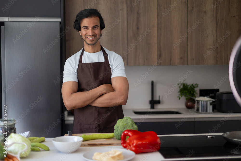 Smiling indian chef in apron standing with crossed arms in a modern kitchen. Smiling indian chef in apron standing with crossed arms in a modern kitchen.
