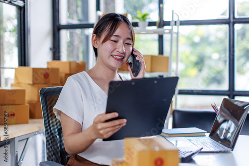 Wallpaper Mural Young asia seller woman happy work on laptop busy cellphone call chat to customer at home office desk use digital tablet computer in SME online store social e-commerce sale page service web support.
 Torontodigital.ca