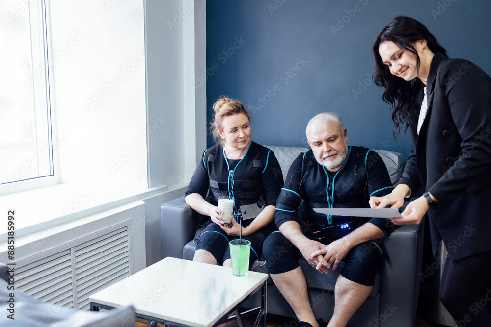 Fototapeta premium Secretary of fitness club offers elderly couple to choose workouts.