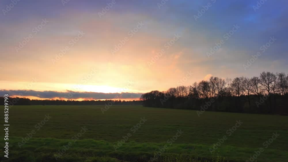 Stunning sunset over a peaceful green field with a backdrop of trees; perfect for serene landscape visuals. Stunning sunset over a peaceful green field with a backdrop of trees; perfect for serene landscape visuals.