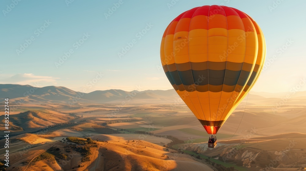 A vibrant hot air balloon is floating gently over an expansive landscape with rolling hills and mountains in the background during a beautiful golden hour. A vibrant hot air balloon is floating gently over an expansive landscape with rolling hills and mountains in the background during a beautiful golden hour.