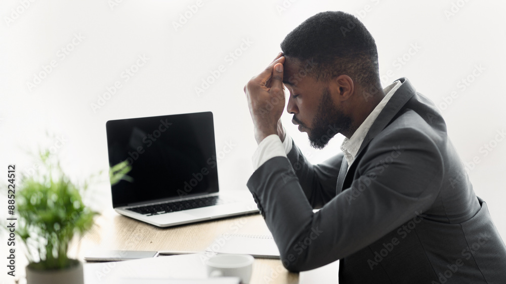 A businessman sits at a desk, his head in his hands, looking stressed. A businessman sits at a desk, his head in his hands, looking stressed.