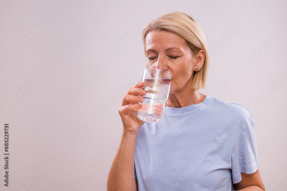 Portrait of happy mature woman drinking water on a gray background. Portrait of happy mature woman drinking water on a gray background.