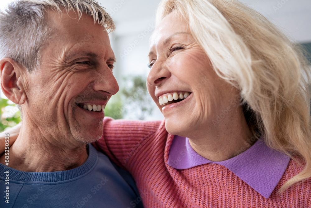 Cheerful blond senior woman with arm around man at home Cheerful blond senior woman with arm around man at home