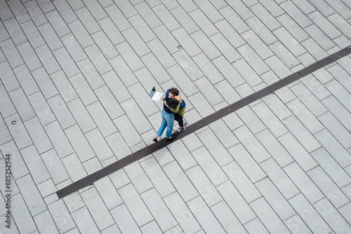 Colleagues embracing on paved footpath