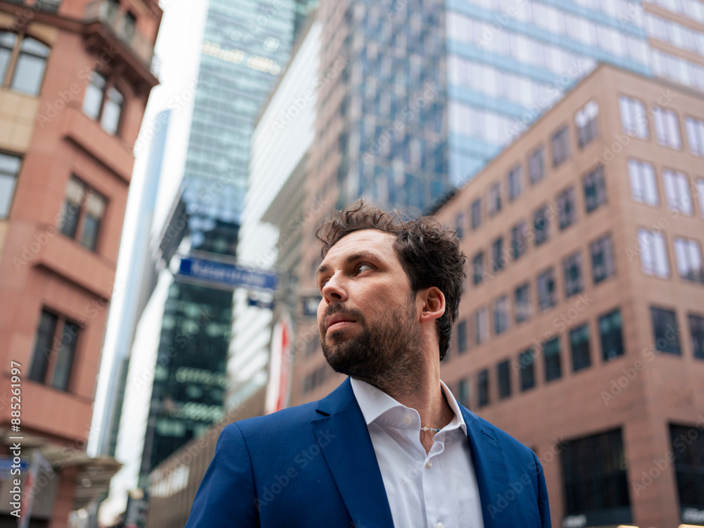 Bearded businessman looking away in front of modern skyscrapers Bearded businessman looking away in front of modern skyscrapers