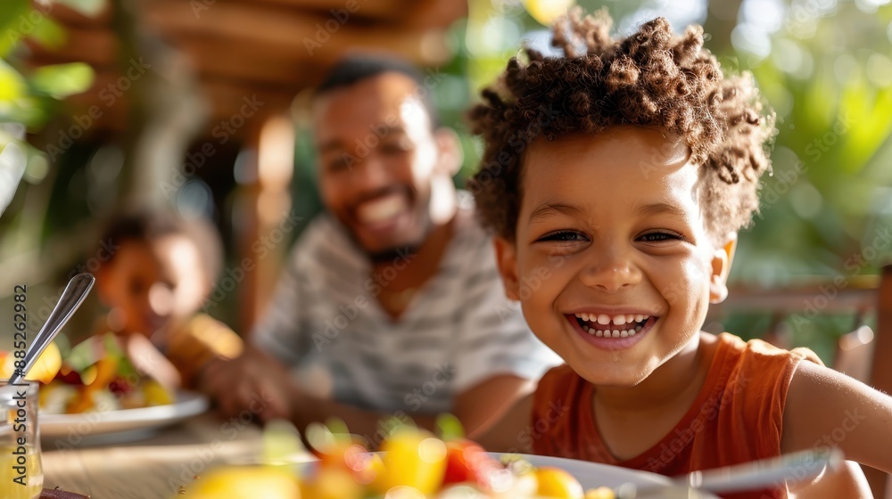A boy shares a joyful smile while sitting at a table with a blurred family in the background, capturing a heartwarming moment of family togetherness and happiness. A boy shares a joyful smile while sitting at a table with a blurred family in the background, capturing a heartwarming moment of family togetherness and happiness.