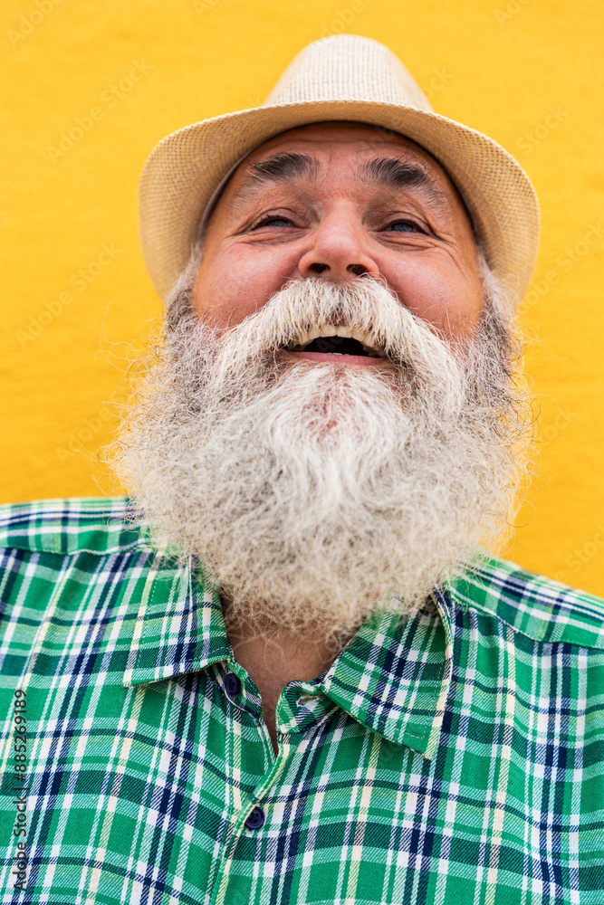 Hipster senior man laughing in front of wall Hipster senior man laughing in front of wall