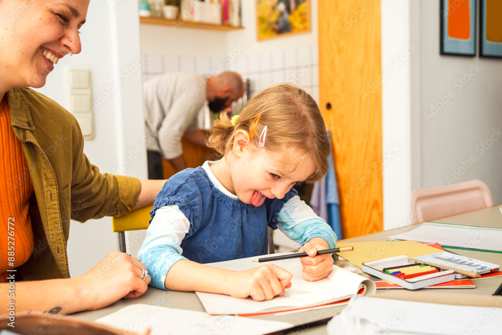 Happy woman homeschooling daughter sitting at table Happy woman homeschooling daughter sitting at table