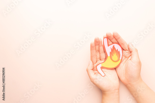 Human stomach burn with acid reflux and fire made from paper on hands. Gastroesophageal reflux disease (GERD) or heartburn symptoms. Gastrointestinal system disease and digestive problems.