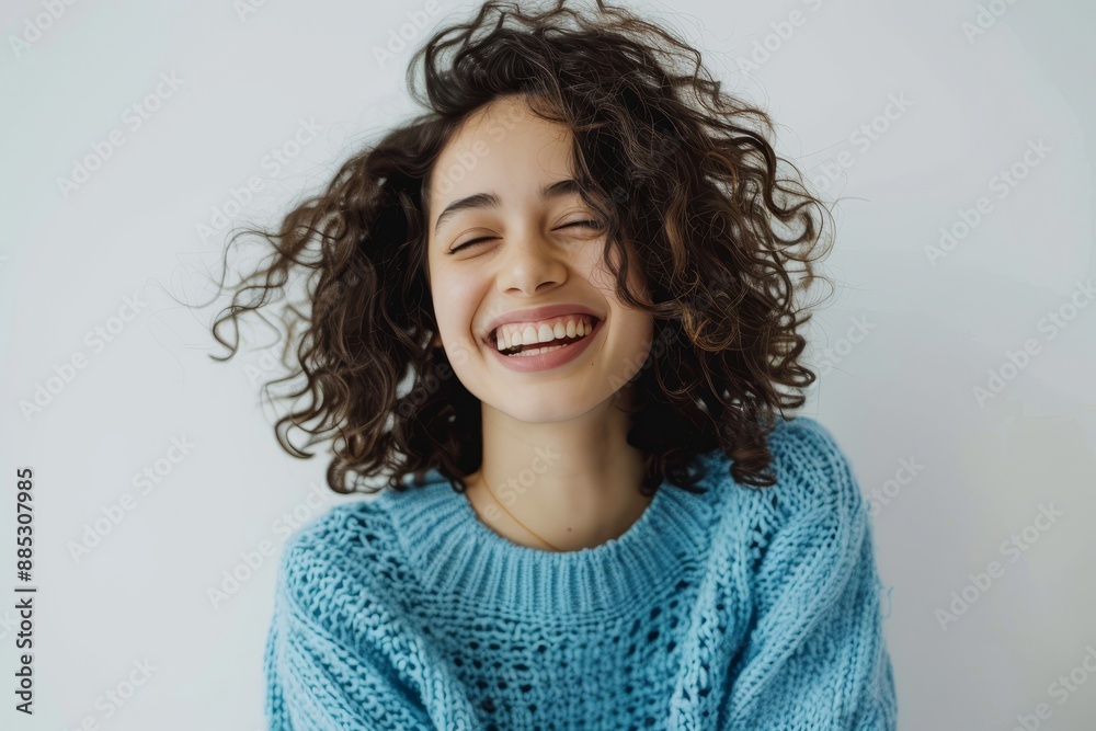 Female with curly hair wearing a light blue sweater. Having a positive emotion and feeling good about herself. Female with curly hair wearing a light blue sweater. Having a positive emotion and feeling good about herself.