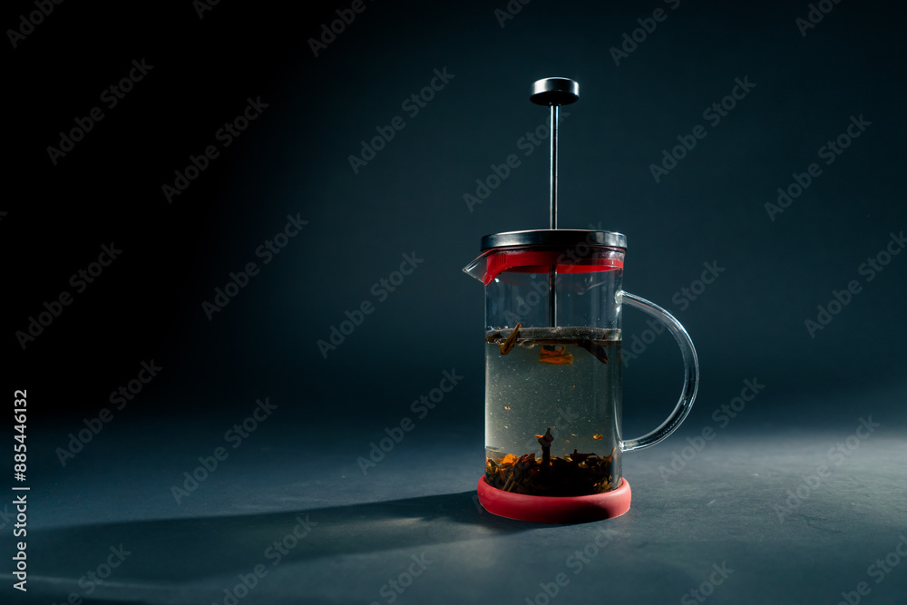 Obraz premium on a dark blue background with side lighting there is glass modern teapot with a press brewing green tea