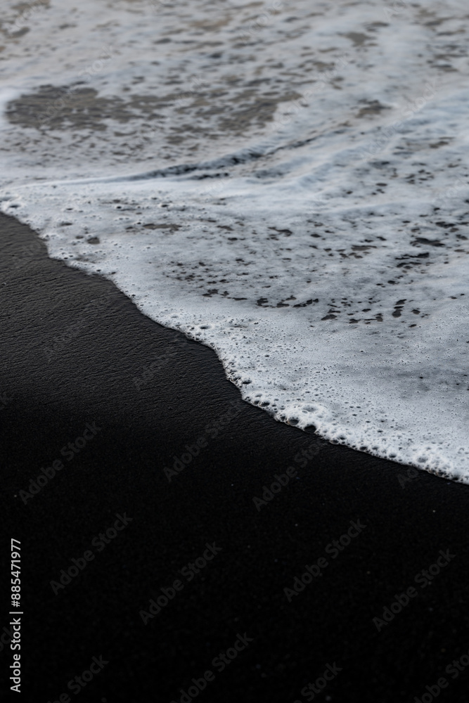 Close-up view of some waves crashing on a black sand beach. Natural background, wallpaper. Iceland.