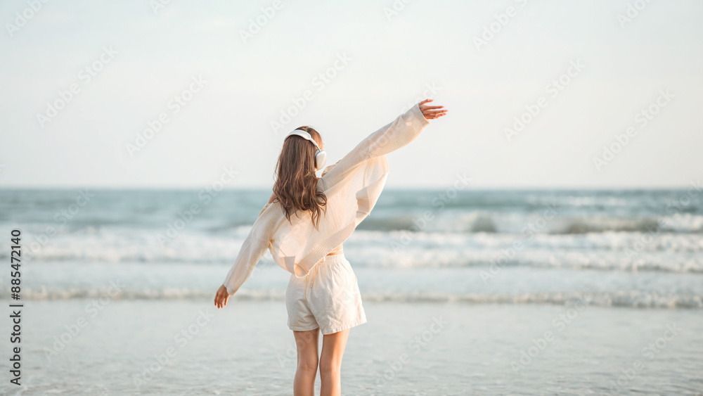 Relax asian woman wearing headphones walking in the sea beach at golden sunset - Female tourist listening to music on summer vacation Relax asian woman wearing headphones walking in the sea beach at golden sunset - Female tourist listening to music on summer vacation