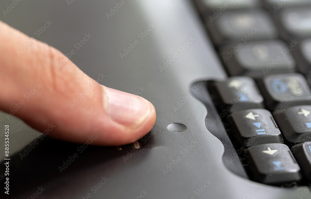 Man using a fingerprint scanner module built into a laptop, finger sliding on the fingerprint sensor detail closeup, one person. Biometric authentication, authenticating using a finger print signature Man using a fingerprint scanner module built into a laptop, finger sliding on the fingerprint sensor detail closeup, one person. Biometric authentication, authenticating using a finger print signature