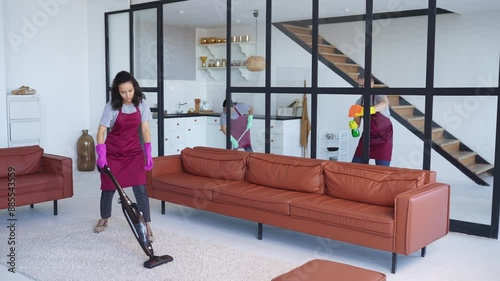 Timelapse of three cleaners meticulously disinfect, sanitize, and vacuum a stylish living room, showcasing professional cleaning expertise