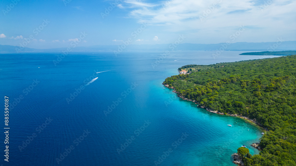 A serene and picturesque beach with turquoise waters, captured by drone on the island of Krk near Glavotok. A boat can be seen drifting on the crystal-clear water, creating a perfect haven for relax