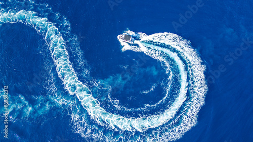 Fotografie An aerial shot captured by a drone showing a boat making a circular turn in the vibrant blue waters near Cres island