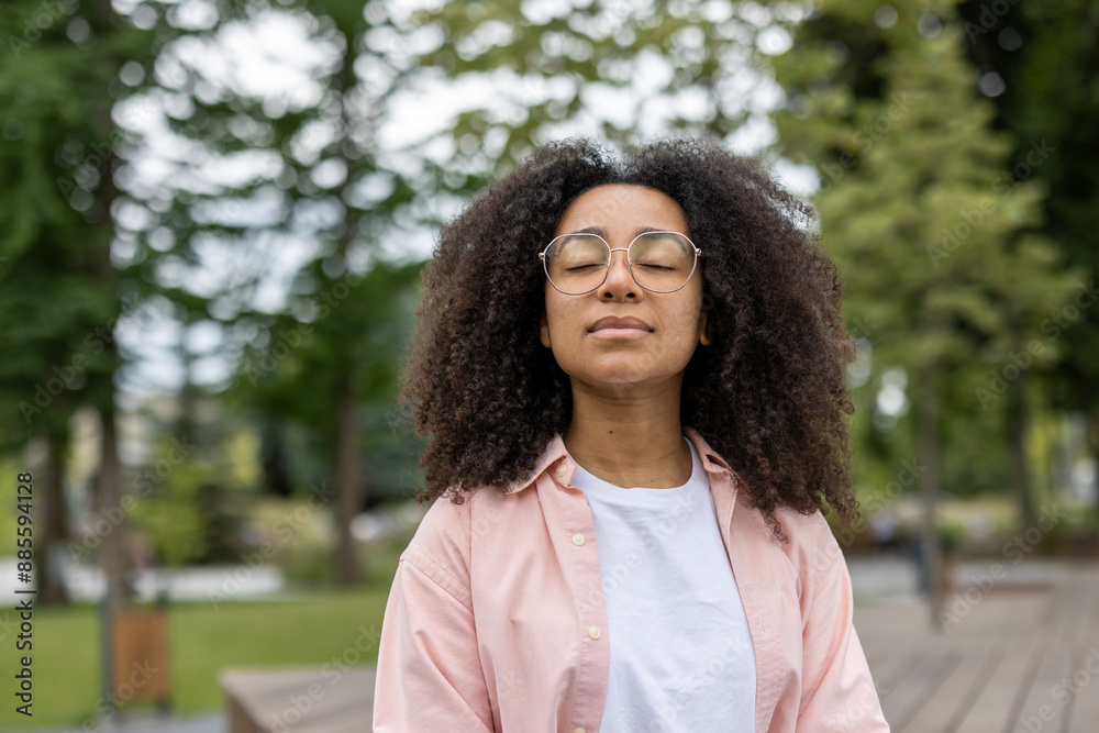Young woman student taking a moment to meditate outdoors in a tranquil park setting, with eyes closed and relaxed expression. Scene captures peaceful and serene atmosphere. Young woman student taking a moment to meditate outdoors in a tranquil park setting, with eyes closed and relaxed expression. Scene captures peaceful and serene atmosphere.