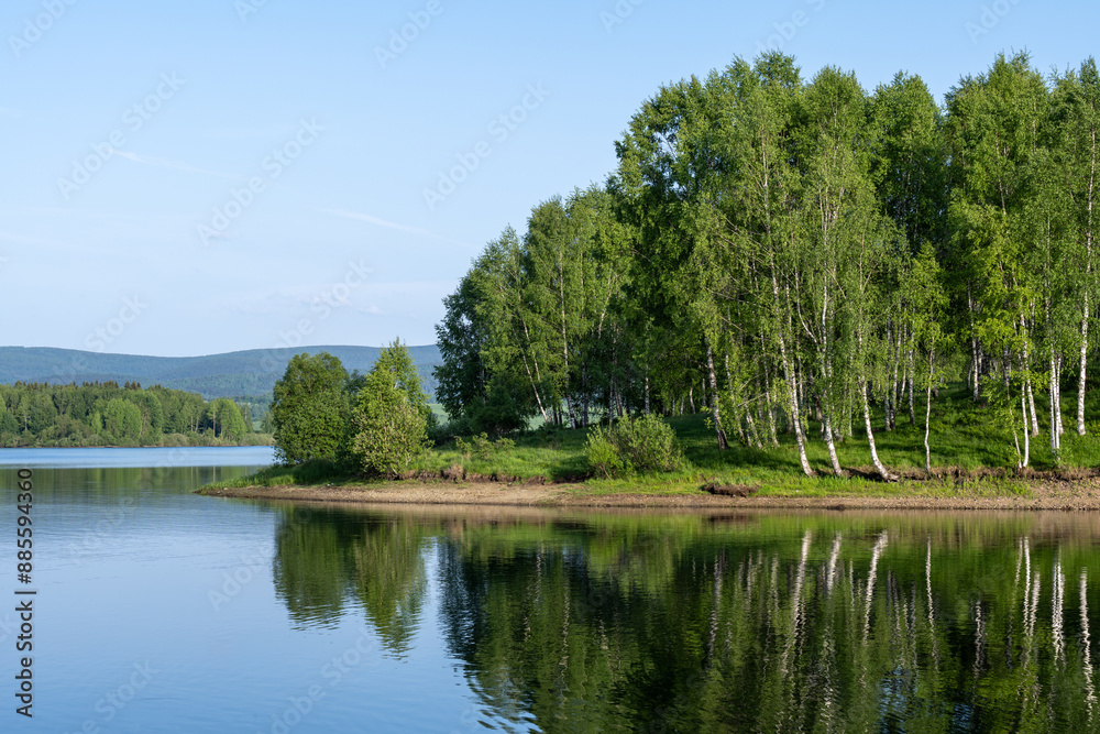 Vlasina lake scenery with beautiful clouds in the blue sky. Beautiful semi-artificial lake in Southeast Serbia. Reflection of a birch tree in the Vlasina Lake. Vlasina lake scenery with beautiful clouds in the blue sky. Beautiful semi-artificial lake in Southeast Serbia. Reflection of a birch tree in the Vlasina Lake.