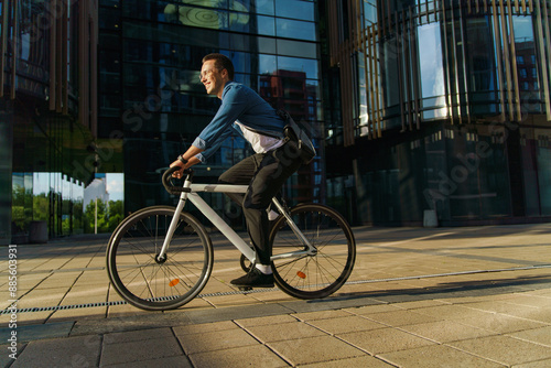 A young man joyfully riding a bicycle in an urban area, illuminated by the evening sun.