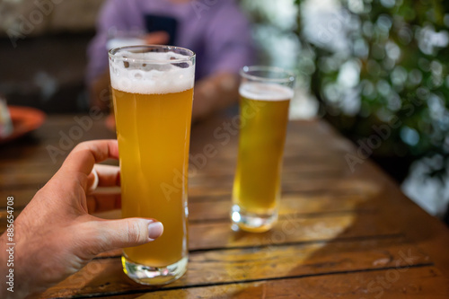 The beers have just been brought to the table, the evening with friends begins. One has stretched out his arm to grab a glass. Friendship, conviviality, joy of life. photo