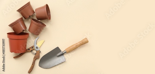 Pots, pruner and shovel on beige background with space for text photo