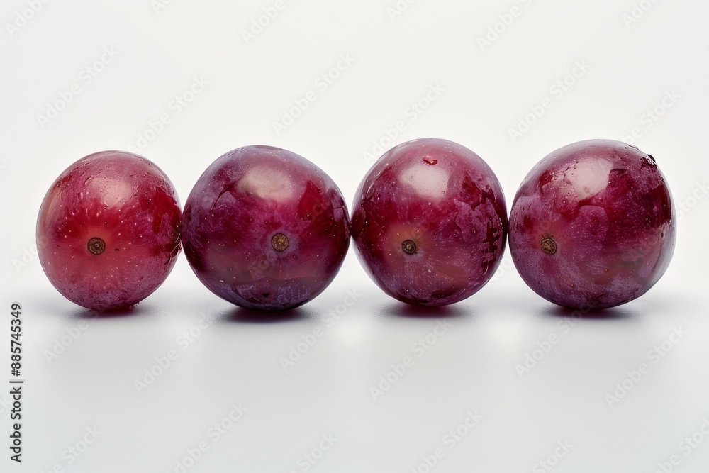 Four whole grapes are placed on a clean white surface, showcasing their vibrant purple color. The grapes are plump and ripe, with no stems or leaves. Four whole grapes are placed on a clean white surface, showcasing their vibrant purple color. The grapes are plump and ripe, with no stems or leaves.