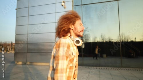 young latin man looks at watch and starts running because he is late at sunset between skyscrapers