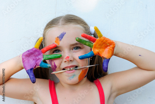 beautiful little girl artist in paints cheerful and funny mischievous