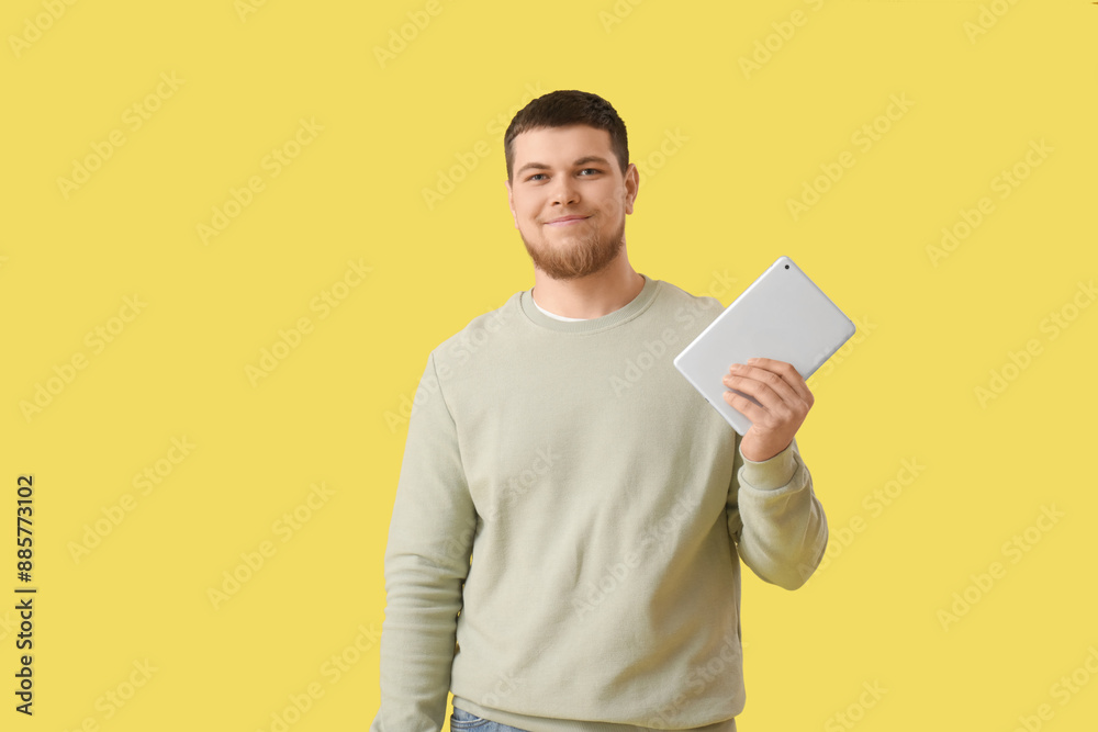 Young bearded man with tablet computer on yellow background Young bearded man with tablet computer on yellow background