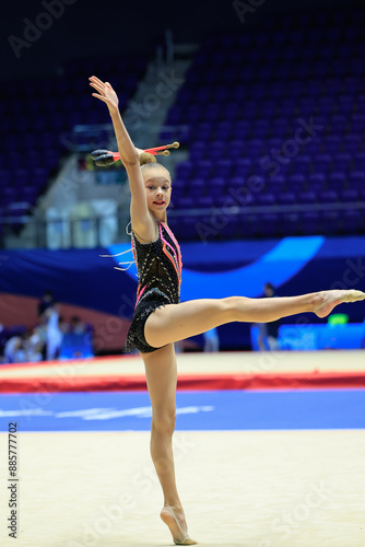 A skilled rhythmic gymnast showcases her agility and accuracy while twirling a club in graceful movement