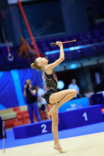 A gymnast with clubs shows talent, flexibility, and grace at a rhythmic gymnastics competition