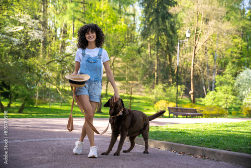 Slim young woman in shorts on a walk with her dog in the park