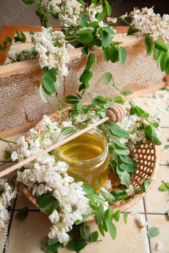 still life of a full jar of transparent yellow ocacia honey on the table against the background of wax honeycombs, organic enriched beekeeping product for alternative medicine, high quality photo photo