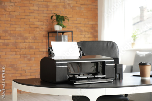 Modern printer with coffee cup on desk in office
