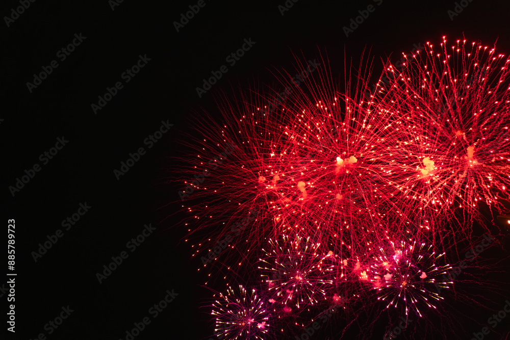 Rad fireworks with smoke over the black sky. Low key exposure.