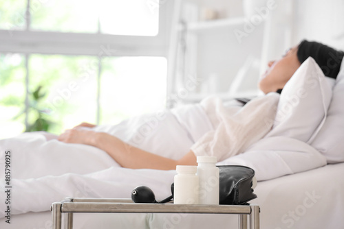 Pill bottles with sphygmomanometer on table in hospital ward, closeup