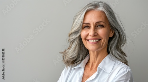 Elegant Senior Woman with Gray Hair and Bright Smile in White Shirt on Gray Background