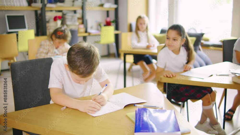 An elementary school boy is doing classwork in his notebook, and his classmate, a girl, is asking him for a pen. An elementary school boy is doing classwork in his notebook, and his classmate, a girl, is asking him for a pen.