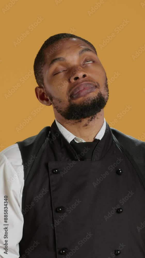 Vertical Video Spiritual waiter in apron praying to Jesus Christ with belief, being hopeful for good luck against yellow background. Restaurant staff holding hands in a prayer to talk to God. Camera A