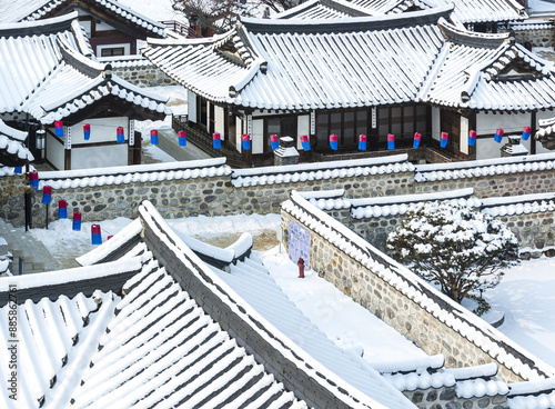 Jung-gu, Seoul, South Korea - January 20, 2017: High angle and winter view of snow covered tile roof of tile houses with traditional Korean lanterns at Namsangol Hanok Village
 photo