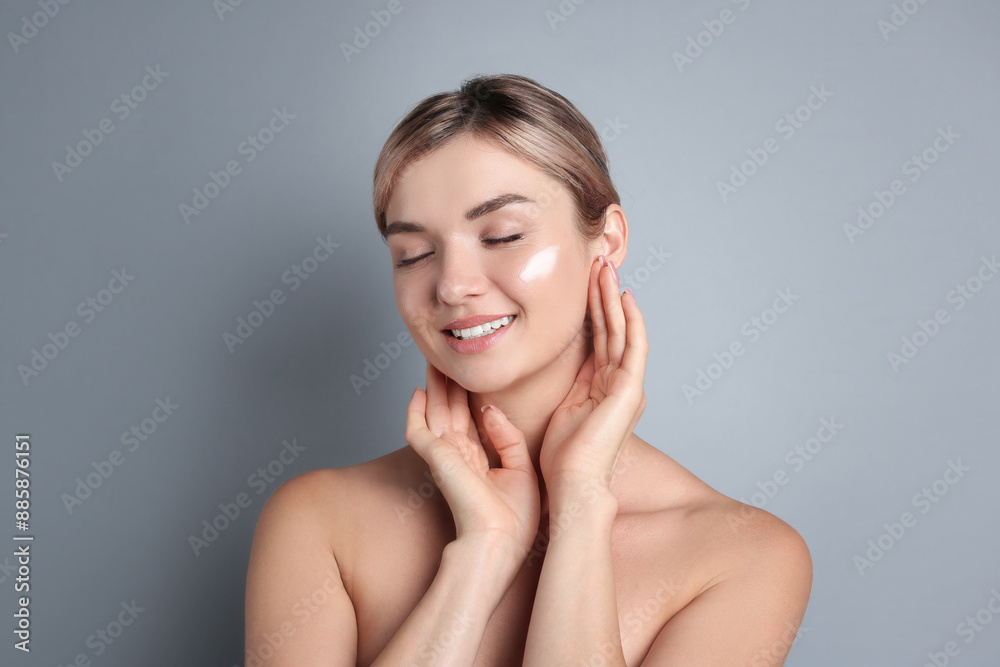Beautiful woman with cream on her face against gray background Beautiful woman with cream on her face against gray background