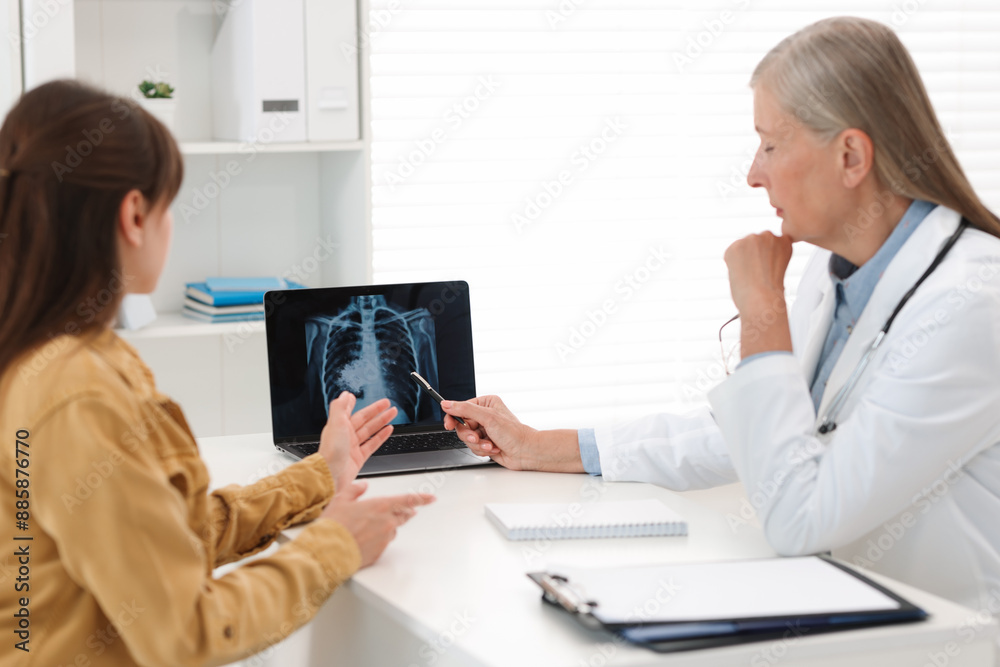 Lung cancer. Doctor showing chest x-ray on laptop to her patient in clinic Lung cancer. Doctor showing chest x-ray on laptop to her patient in clinic