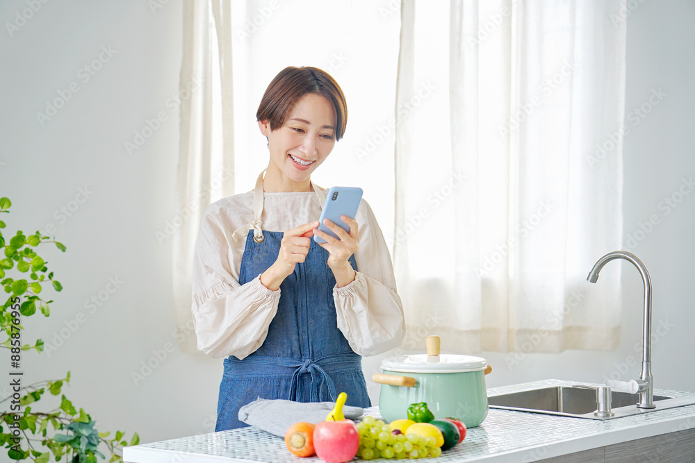 キッチンでスマホを見る女性