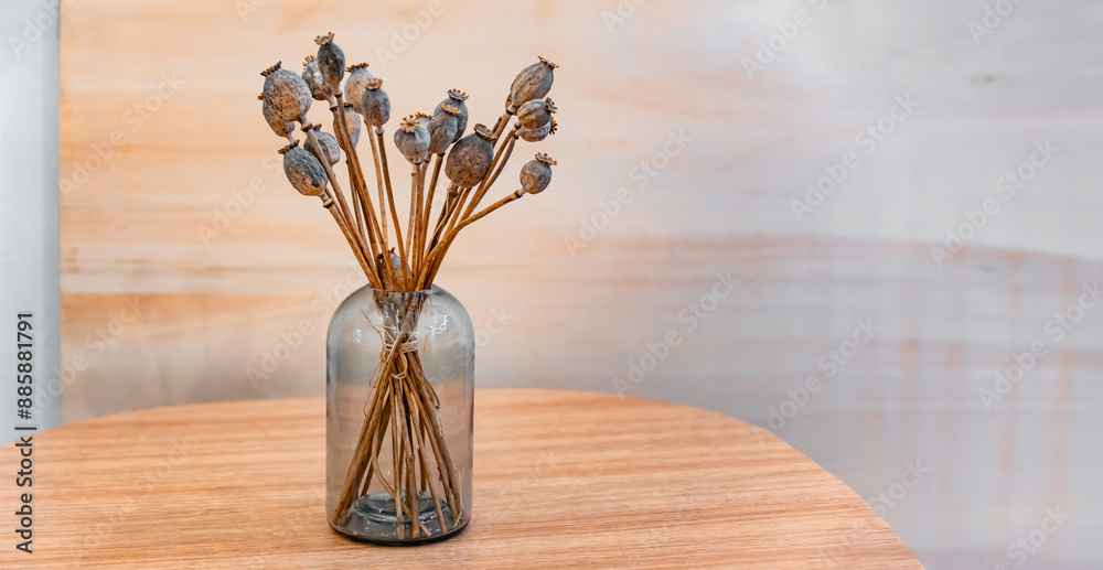 Dried poppy flowers. Bouquet of dried flowers in a glass vase on a wooden table. Copy space