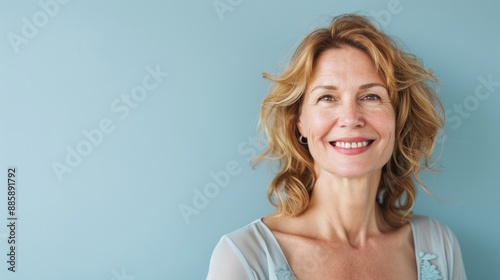 Half-body photo of a middle-aged woman smiling confidently, with a solid light blue background and ample copy space on the right side